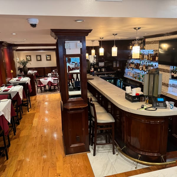 Pietro's Italian restaurant interior with a fully stocked bar and dining area with set tables.