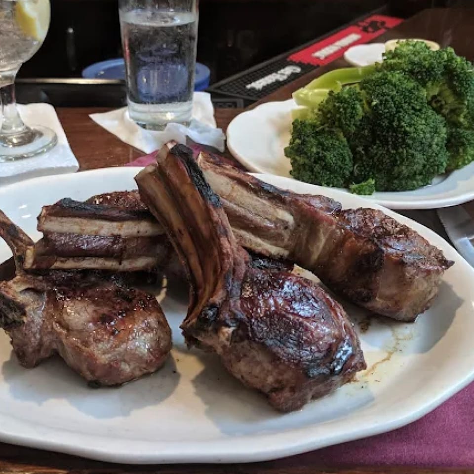 Grilled lamb chops with a side of steamed broccoli and drinks at Pietro's, an Italian restaurant.