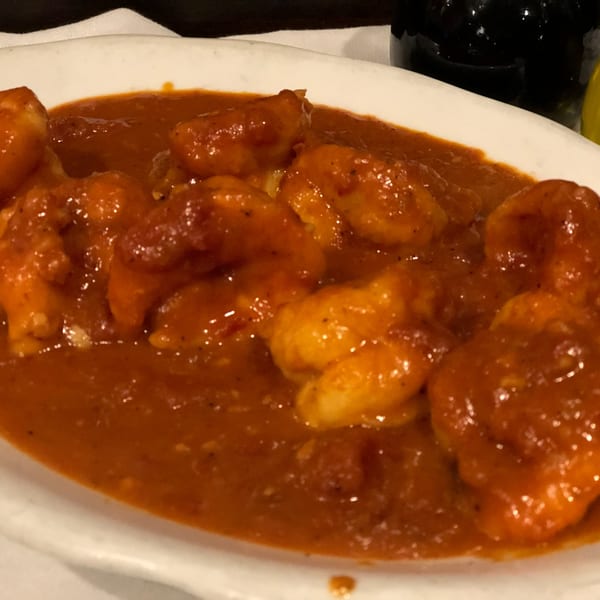Pietros' Italian shrimp dish in a rich, red sauce, served in a white bowl.